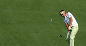 Ian Poulter chips at the first.