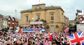 The open top bus pulls up outside the town hall in front of cheering fans.