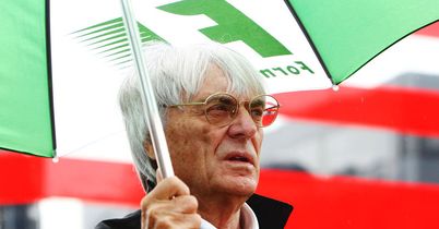 Bernie Ecclestone shelters from the rain.