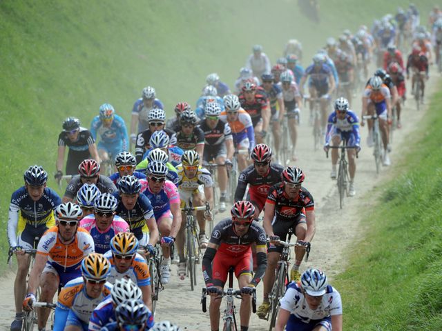 The dust is flying as the riders power over the cobbles
