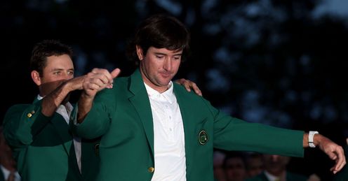 Charl Schwartzel helps winner Bubba Watson into the green jacket.