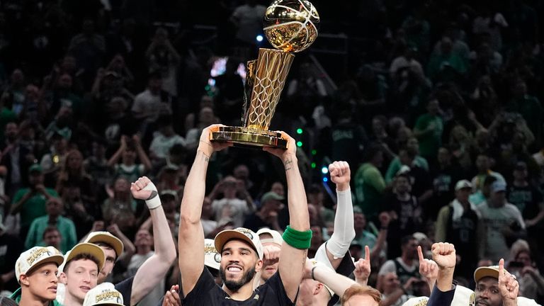 Boston Celtics forward Jayson Tatum holds, center, up the Larry O&#39;Brien Championship Trophy as he celebrates with the team after they won the NBA basketball championship with a Game 5 victory over the Dallas Mavericks, Monday, June 17, 2024, in Boston. (AP Photo/Charles Krupa)