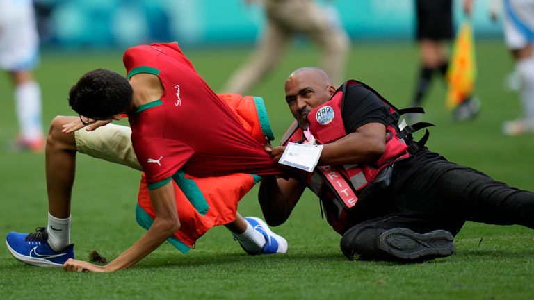 A steward catches a pitch invader during the men&#39;s Group B soccer match between Argentina and Morocco at Geoffroy-Guichard Stadium at the 2024 Summer Olympics, Wednesday, July 24, 2024, in Saint-Etienne, France. (AP Photo/Silvia Izquierdo)