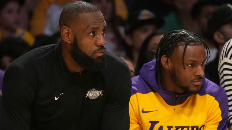 Los Angeles Lakers forward LeBron James guard Bronny James watch play during the first half of an NBA basketball game against the Minnesota Timberwolves, Tuesday, Oct. 22, 2024, in Los Angeles. (AP Photo/Eric Thayer)