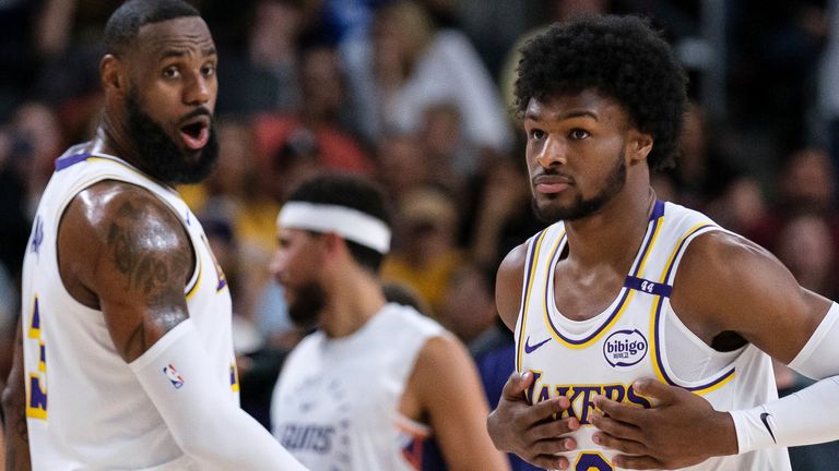 Los Angeles Lakers guard Bronny James (9), right, steps onto the court with Los Angeles Lakers forward LeBron James (23) during the first half of a preseason NBA basketball game Sunday, Oct. 6, 2024, in Palm Desert, Calif. (AP Photo/William Liang)