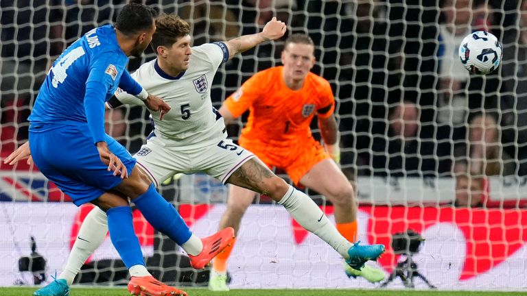 Greece's Vangelis Pavlidis, left, shoots on target past England's John Stones, centre, during the UEFA Nations League Group F soccer match between England and Greece at Wembley Stadium in London, Thursday, Oct. 10, 2024. (AP Photo/Kirsty Wigglesworth)