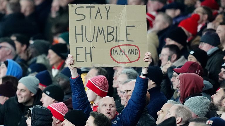 An Arsenal fan holds up a 'stay humble sign' to Erling Haaland