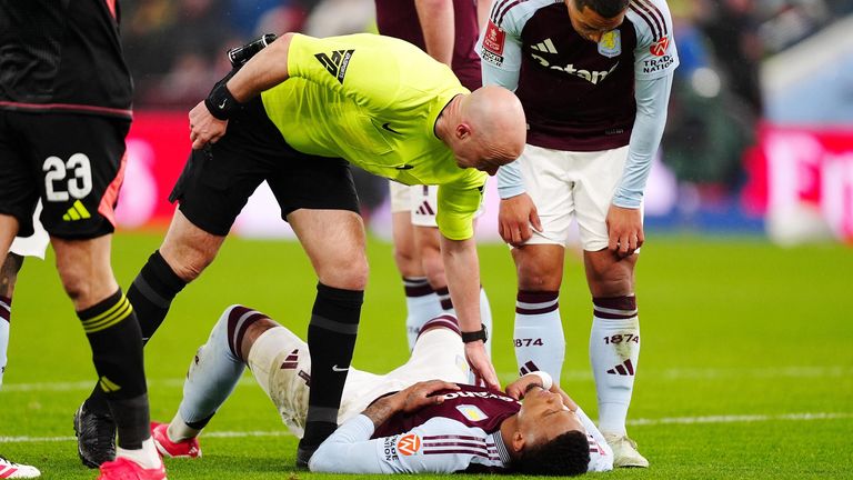 Referee Anthony Taylor checks on the injured Ezri Konsa 