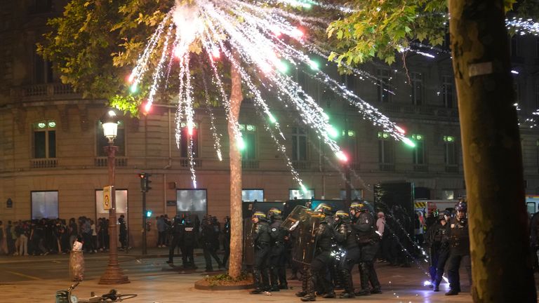 Fireworks explode over riot police officers on the Champs-Elysees 