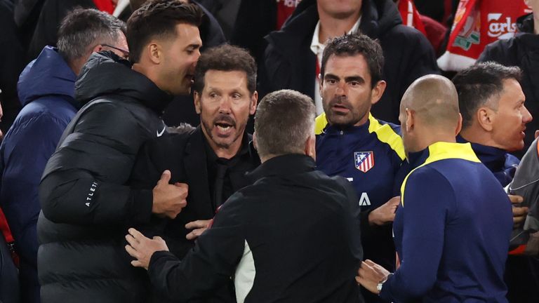 Diego Simeone is pulled away by his Atletico Madrid coaching staff after clashing with a Liverpool fan at Anfield