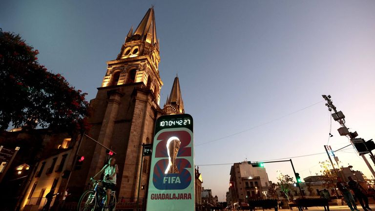 A man rides a bicycle past the Guadalajara Cathedral and a FIFA World Cup countdown
Ulises Ruiz / AFP via Getty Images