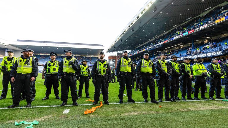 Police at Ibrox separating fans of Rangers and Celtic after they entered the pitch